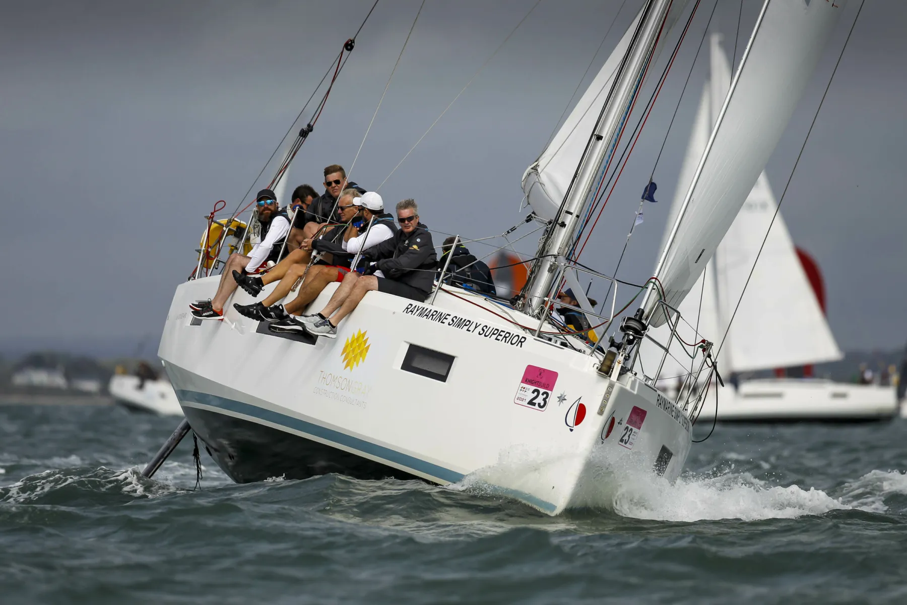 Members of the Thomson Gray Construction Consultants team on board a yacht sponsored by the firm in a sailing challenge - the Little Britain Challenge cup. The boat tilts to the side as it turns.