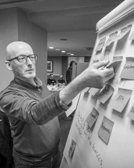 A senior male member of staff at Thomson Gray Construction Consultants works at a flip board using post-its to map out ideas.