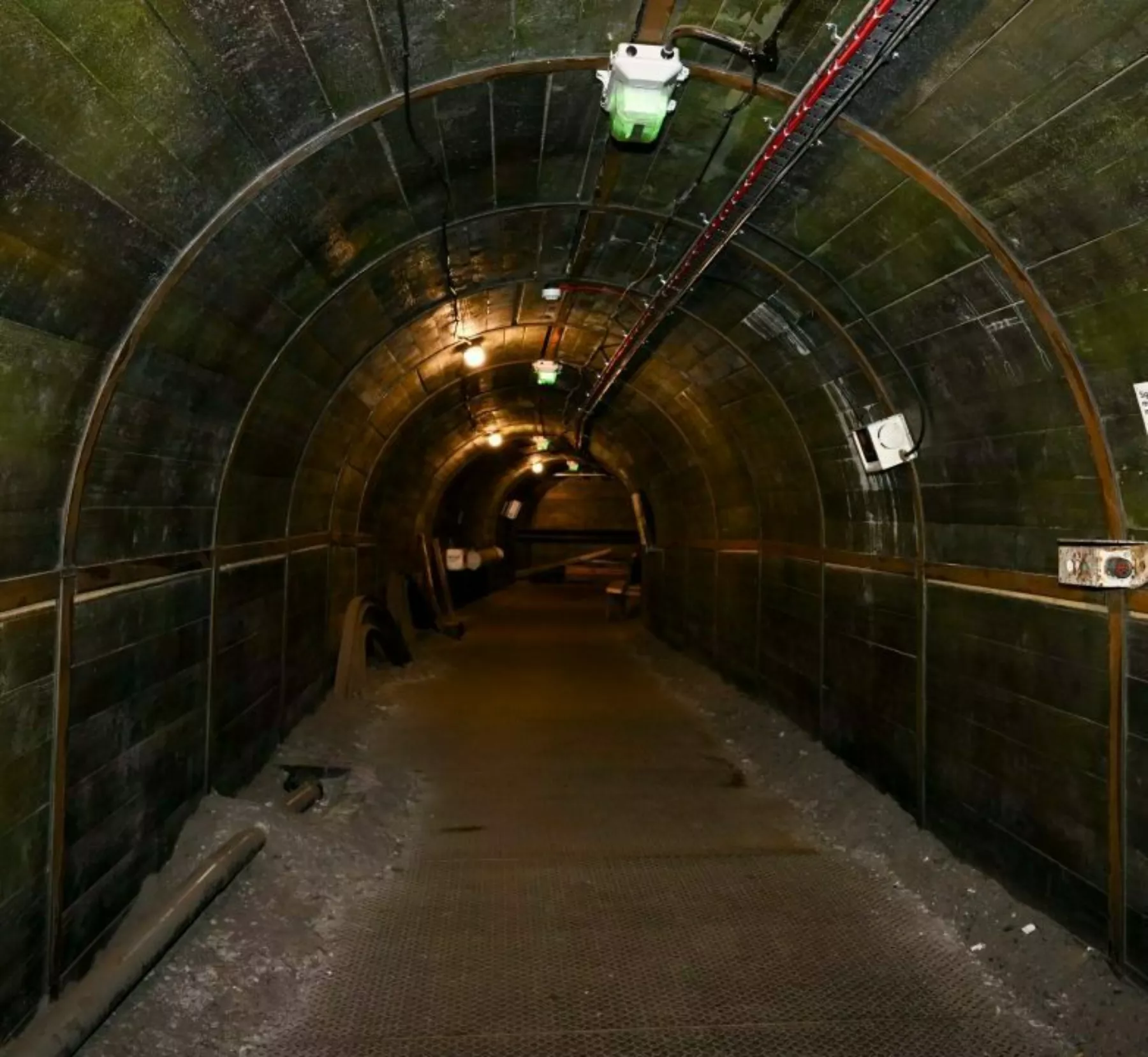 Photograph of empty and disused mine shaft with green tiles and lights on ceiling