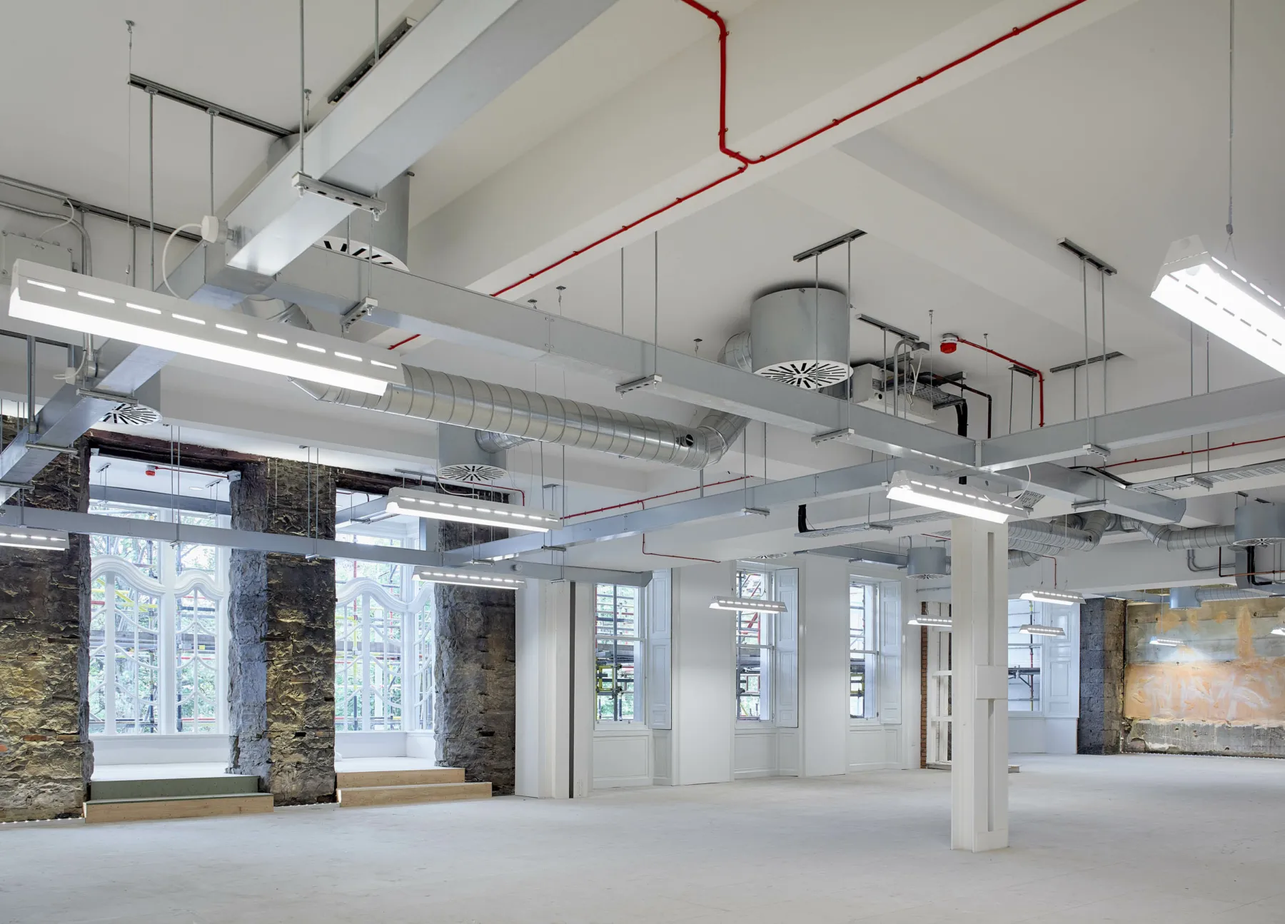Inside a defurbished office in a listed building. Exposed stonework and services are part of the aesthetic, with ducting and wiring visible along with distressed plasterwork.