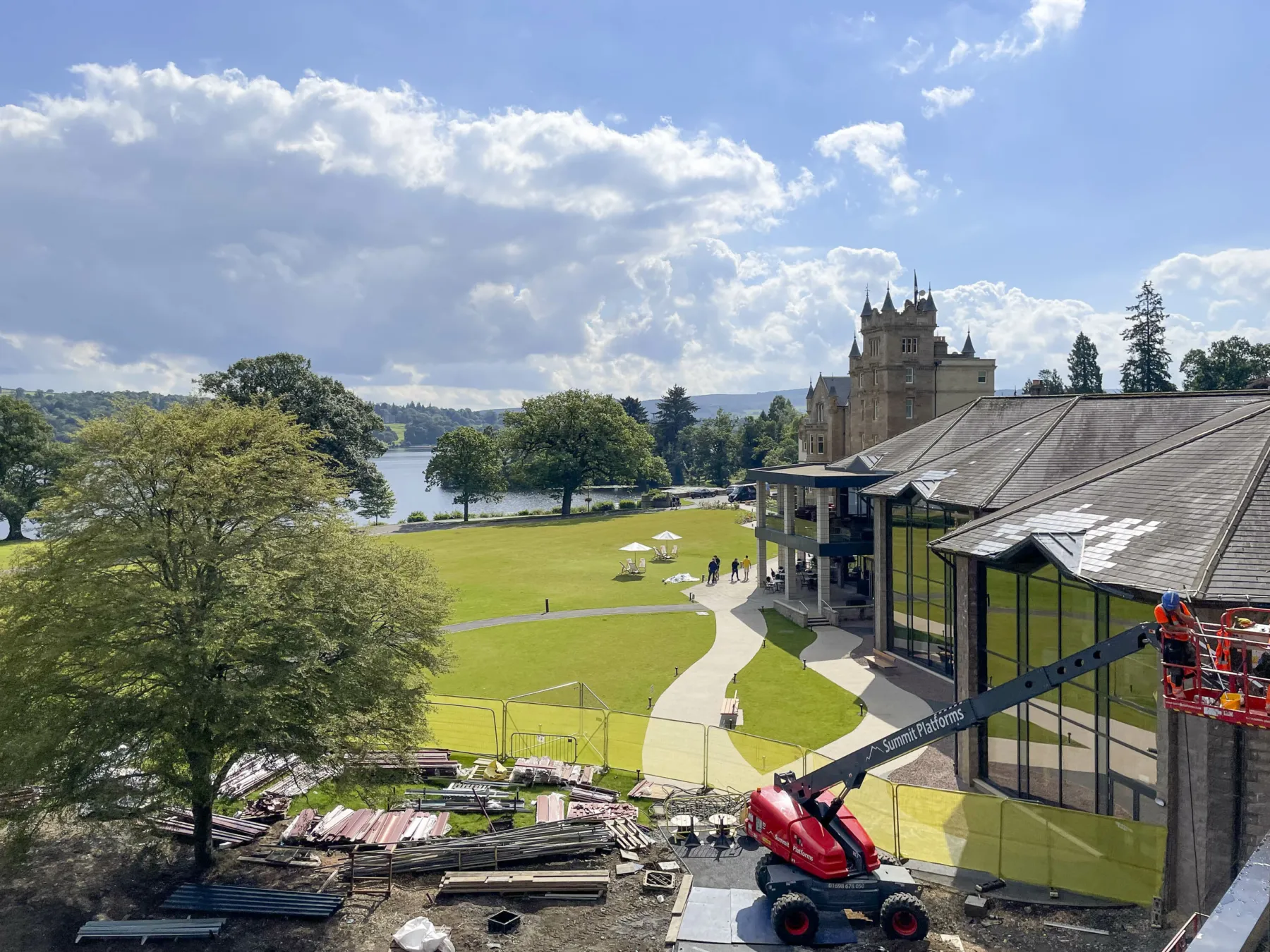 Works underway on a new building at Cameron House Hotel, Loch Lomond. In the background, the historic part of the hotel with newer extensions in front. In the foreground a cherry pickers works on the new building under construction