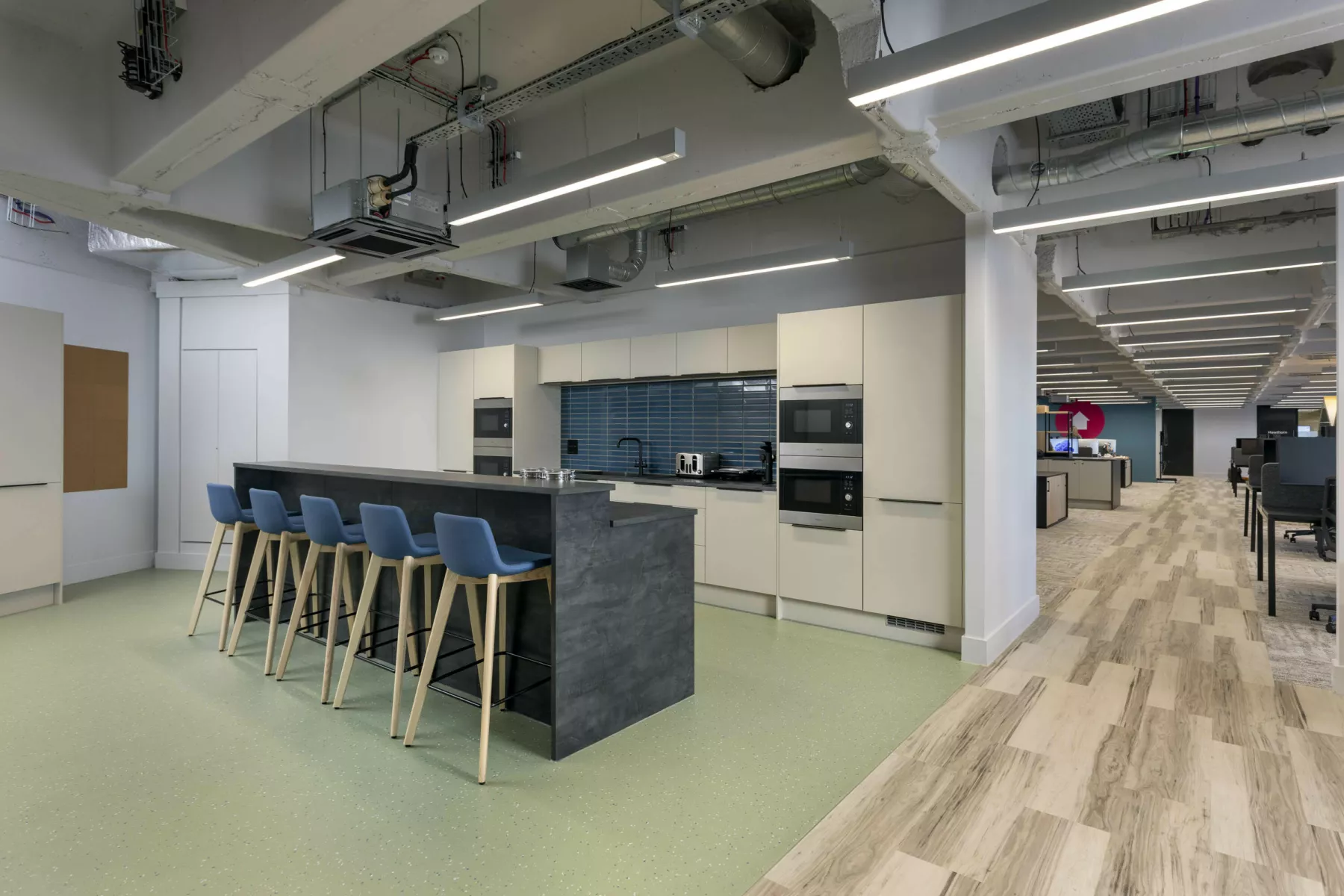 Kitchen area in fully refurbished Cat-B office fit-out for Changeworks, Edinburgh. Bar with high seats, mixed flooring and defurbishment style ceiligh with exposed services.