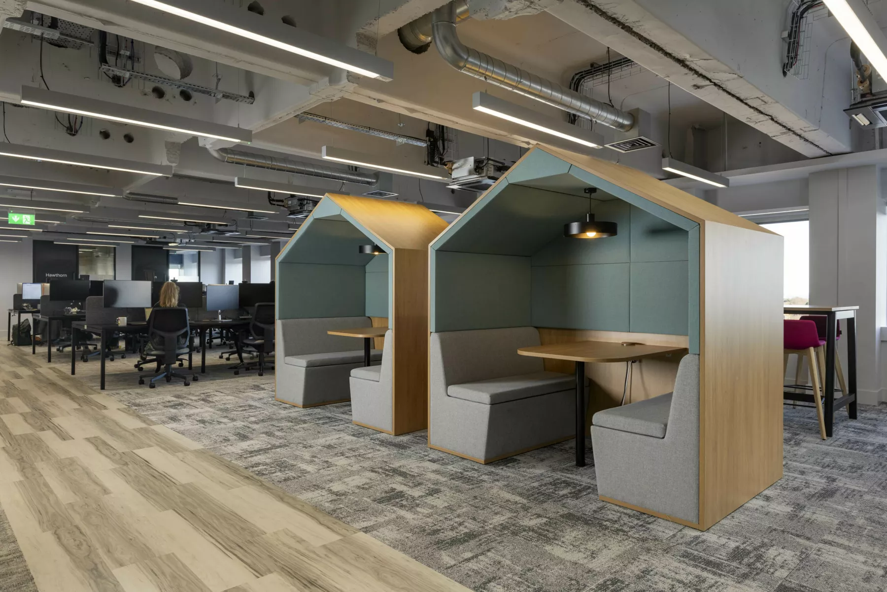 Pod booths within open plan office, refurbished with refurbishment features such as exposed ducting and services. Mixed flooring with areas to provide sound proofing.