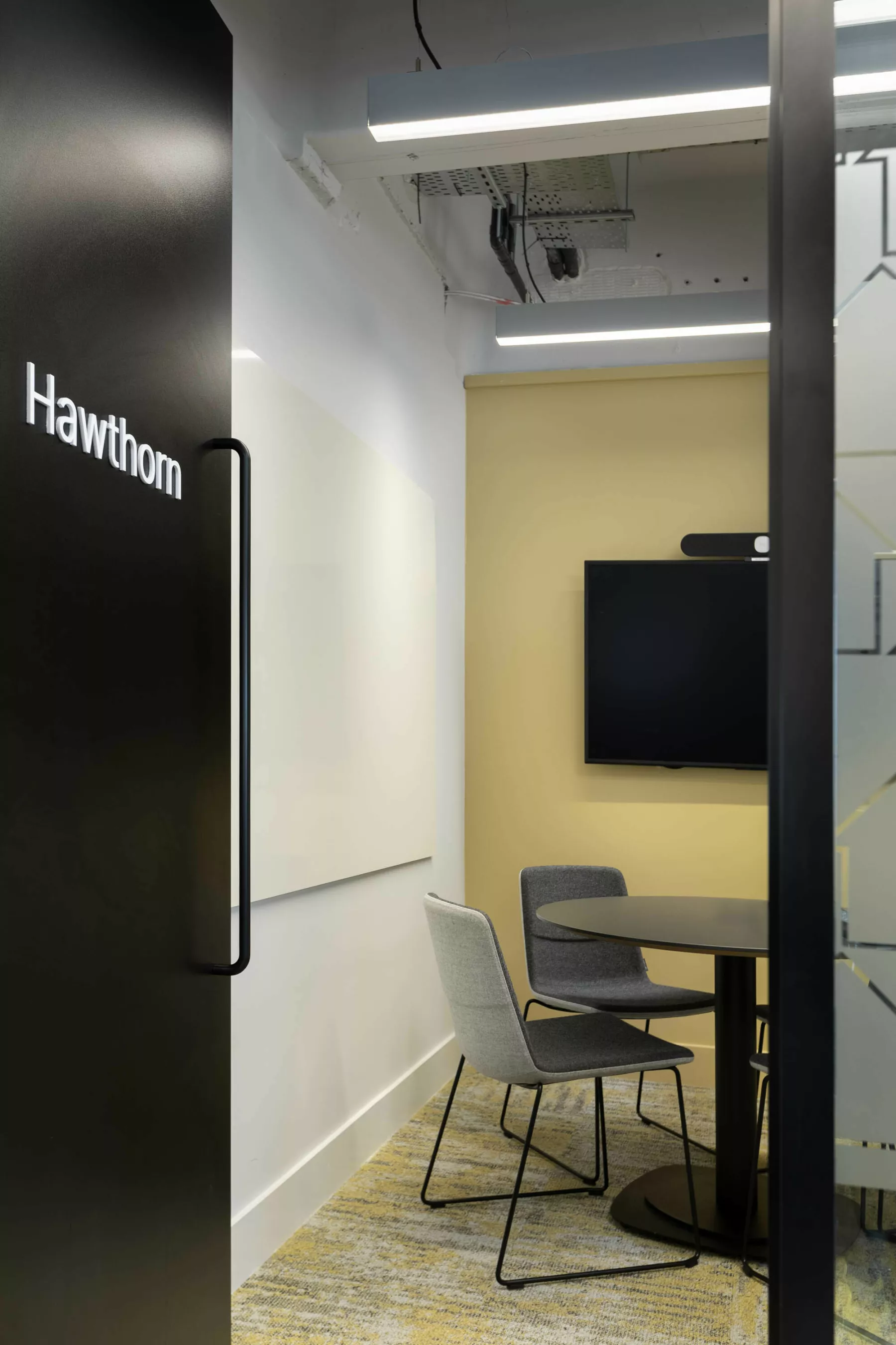 View into the 'Hawthorn' meeting room through an open door at the office newly refurbished for Changeworks, Edinburgh. A smartboard, screen and round meeting table.