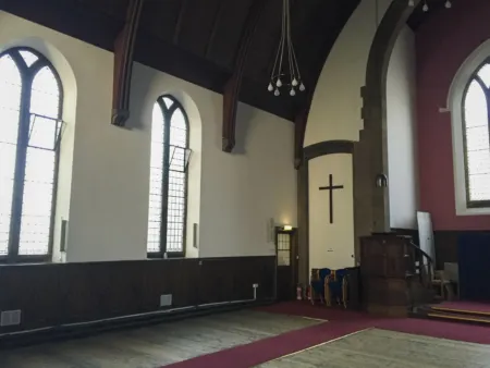 Greyfriars Charteris Centre in the nave prior to refurbishment and conservation work commenced. Carpet borders the wooden floors and the ceiling is dark stained timber panelling.