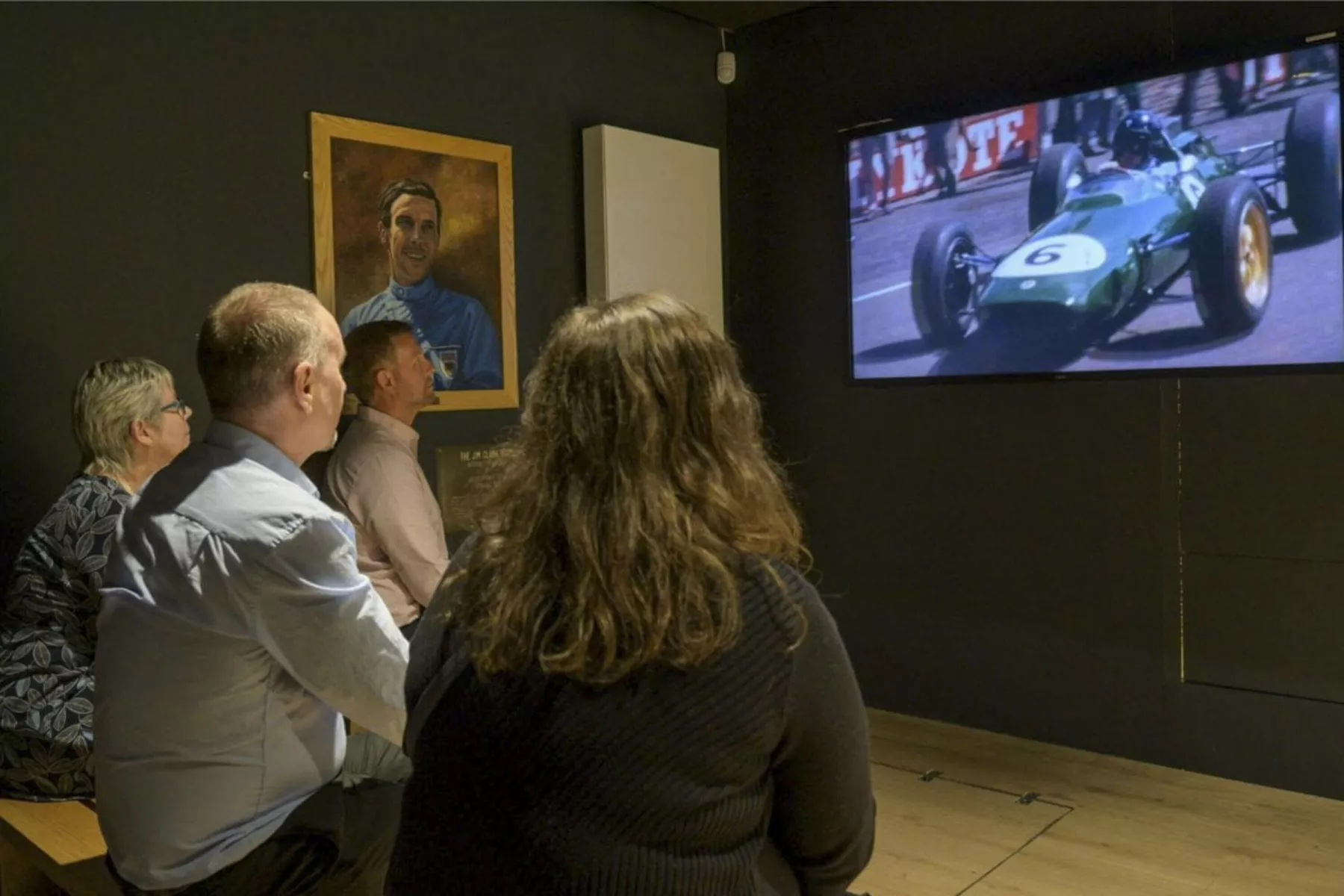 Inside a cinema area at the Jim Clark Motorsport Museum. Visitors watch a film with footage of racing.