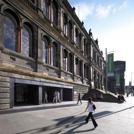 Outside view at pavement level of the National Museum of Scotland, Chamber Street, Edinburgh. Photograph shows the Victorian building with new entrance at street level. visitors are walking in the direction of the entrance across the wide sandstone pavement.