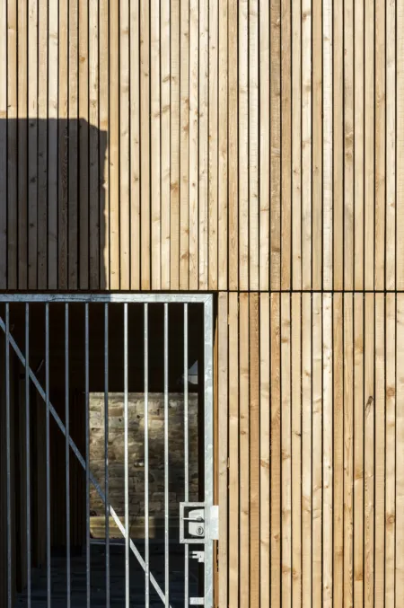 Detail of timber clad wall with simple galvanised steel gate set in.