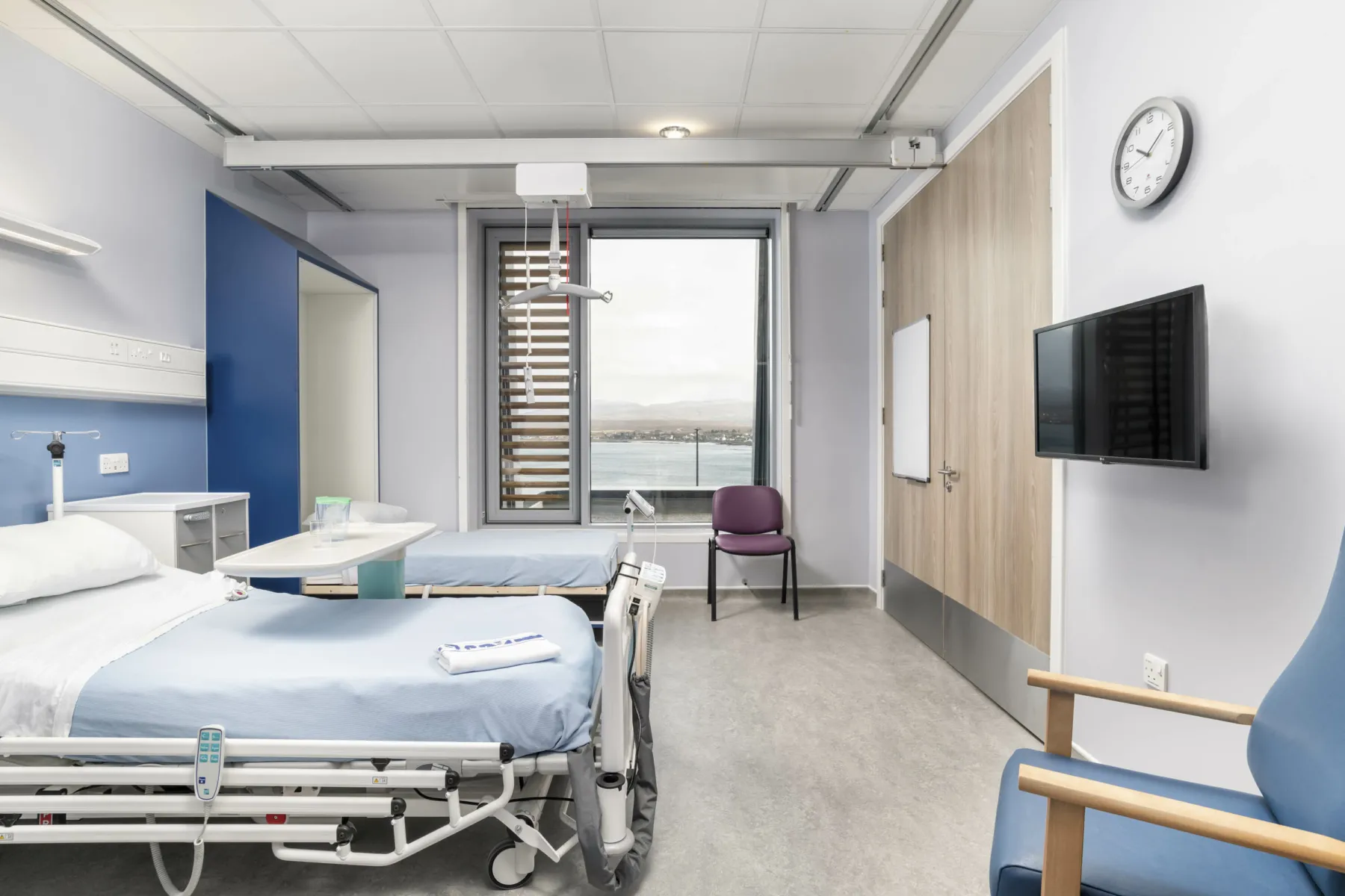 Inside a small ward at the rural new build hospital at Broadford on Skye. Two beds have a view out over the sea and there are chairs for visitors.