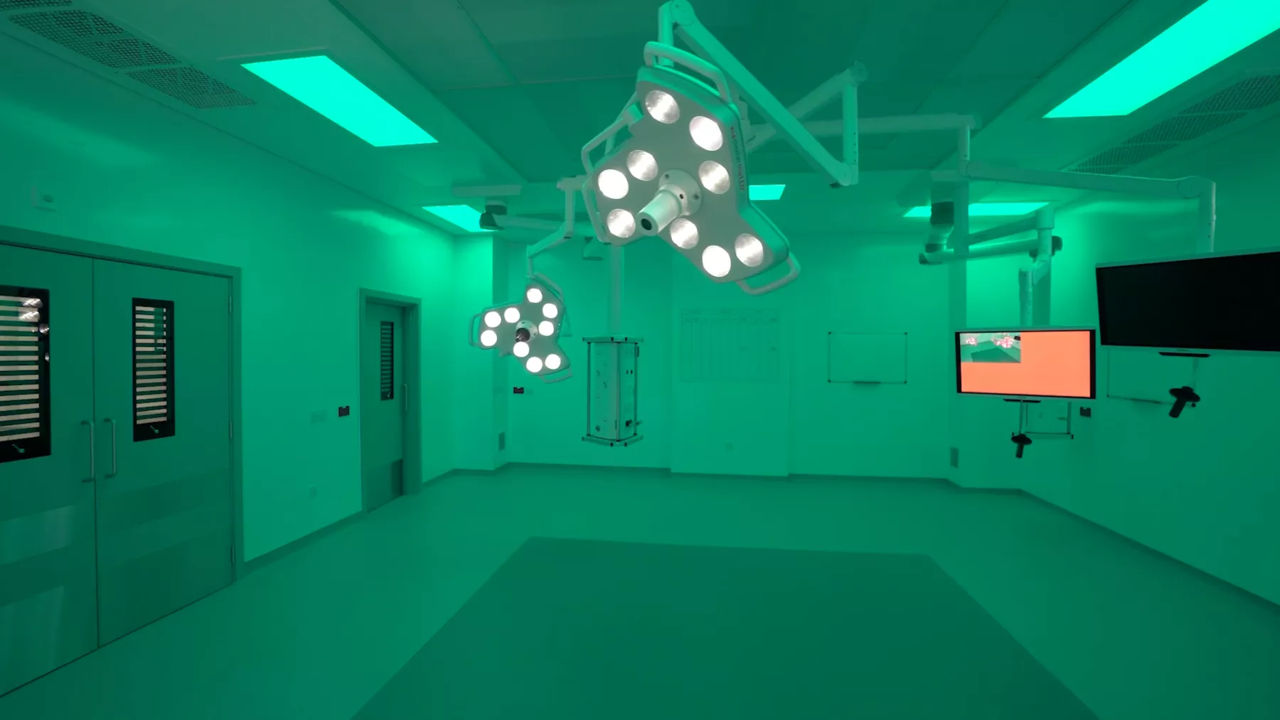 Inside a new operating theatre at the National Treatment Centre - Fife Orthopaedics, Kirkcaldy, Scotland. Theatre lighting and screens. The theatre is flooded with green light. There is no operating table or other equipment.
