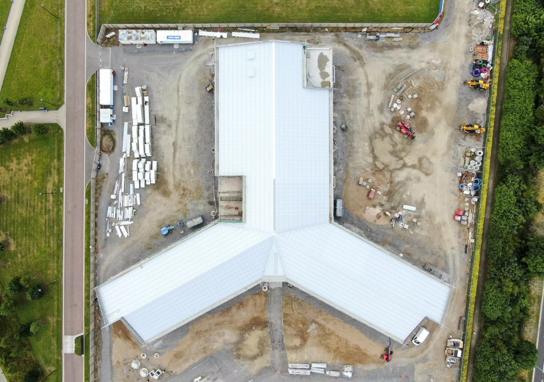 Construction works at the new healthcare facility - the National Treatment Centre - Highland, Inverness. This aerial view in plan shows the building's triad shape with three wings, and prior to its final bronze-gold cladding. Supplies and construction vehicles are around the building, which has had no landscaping yet completed.