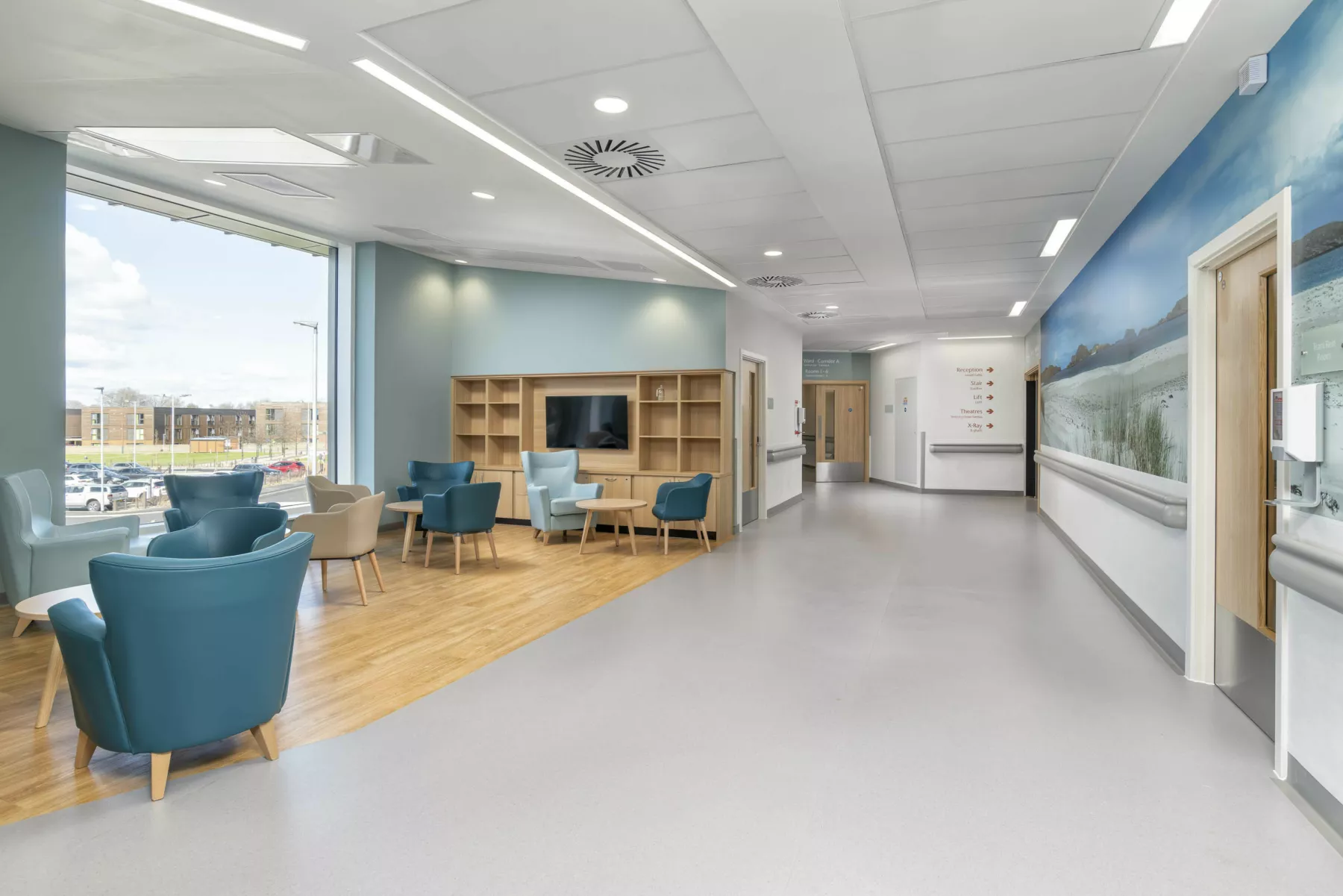 First floor waiting area at National Treatment Centre - Highland. Armchairs in turquoise and tan in an area with wooden floor off the main corridor.
