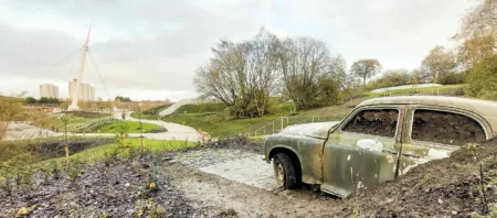 Public art at Stockingfield Bridge. A 1960s Rover is shown half-buried ready to be planted as part of the public park at Stockingfield Bridge