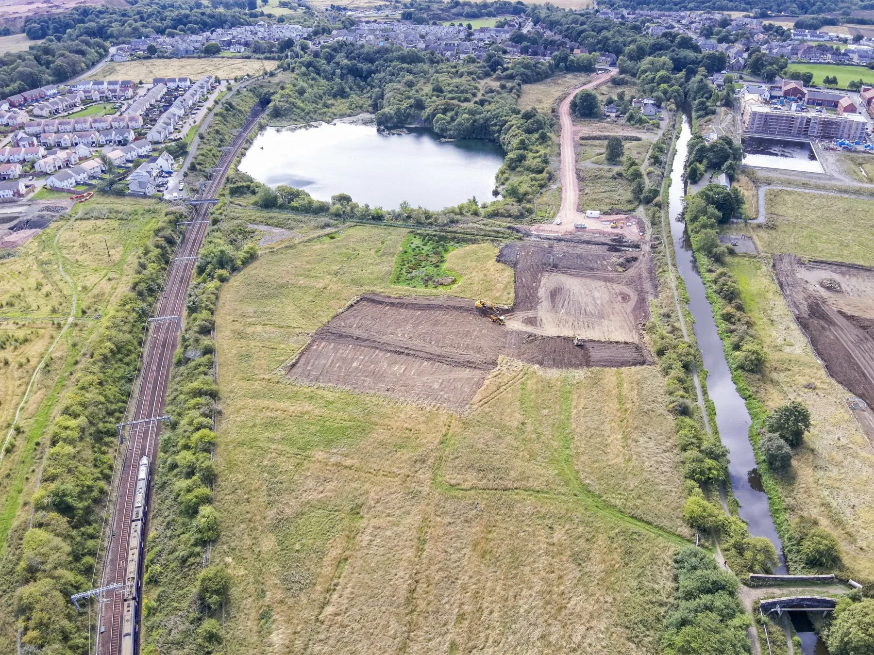 Development underway at Winchburgh with the canal and railway line visible from the air. A flooded quarry is shown alongwith works for new roads and a new marina basin adjoining the canal is just in shot.