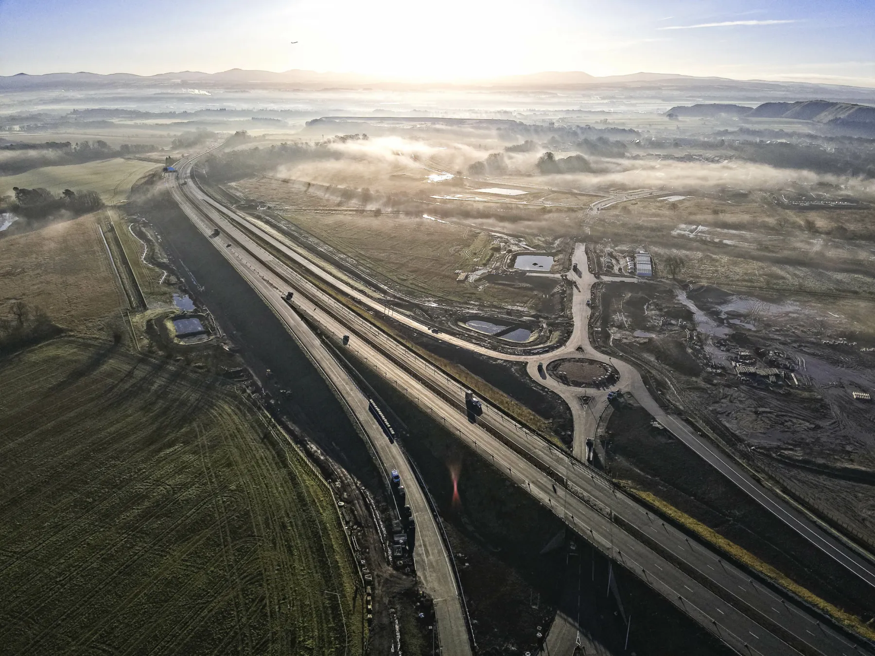 Aerial view of new junction on the M9 at Winchburgh. Early morning mist is settling on the fields surrounding the works. A new roundabout sits behind the motorway. Part of the documentation used by Thomson Gray Construction Consultants during the project.